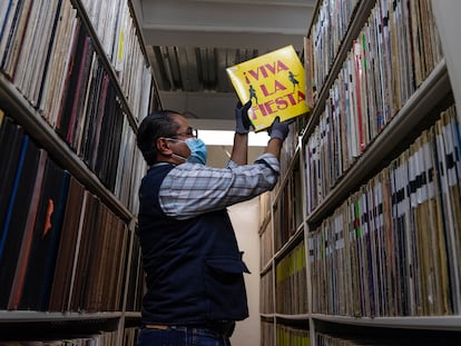 Un empleado encargado de resguardar los documentos sonoros de la Fonoteca Nacional de México saca un vinil de una estantería.