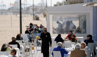 Un camarero atiende las mesas de una terraza en la playa de la Malvarrosa (Valencia).