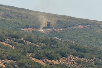 Un bulldozer excava un cortafuegos por la ladera de la montaña para evitar la propagación del incendio.