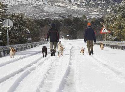 Una pareja camina por la carretera nevada que une Prado Negro con la A-92 en la provincia de Granada.