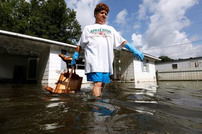 Una mujer transporta mobiliario dañado por una calle inundada, en St. Amant, Luisiana (EE.UU)