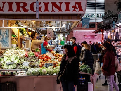 Varias personas compran en un puesto de fruta y verdura en el Mercado Central de Valencia.