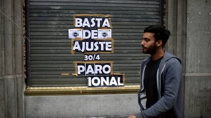 Un joven pasa frente a un local en Buenos Aires que tiene une pegatina donde se anunciaba la huelga general que se realizó el pasado 30 de abril.