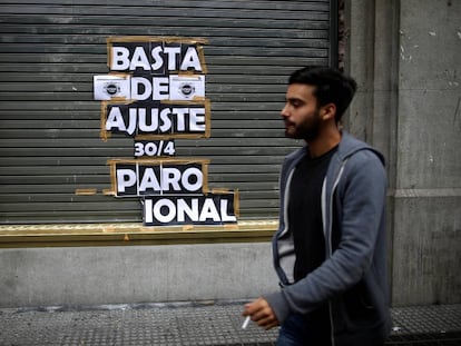 Un joven pasa frente a un local en Buenos Aires que tiene une pegatina donde se anunciaba la huelga general que se realizó el pasado 30 de abril.