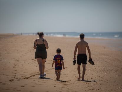 Una familia pasea por la playa de Punta Umbría (Huelva).