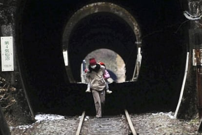 Una mujer con un niño a cuestas atraviesa un túnel en Kesennuma, en la prefectura de Miyagi.