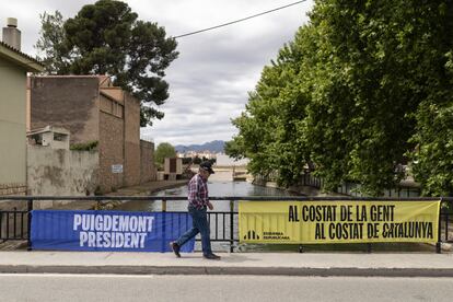 En Jesús (Tortosa), un hombre camina junto a dos pancartas electorales mientras cruza el canal derecho del Ebro por un puente.


