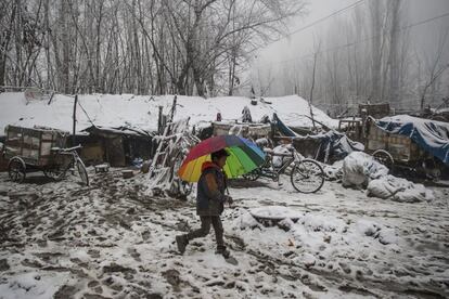 Un niño indio camina con un paraguas por un campo nevado en Srinagar (Cachemira India).