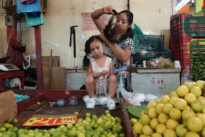 mujer peina a su hija en el mercado de la Merced, en Ciudad de México.