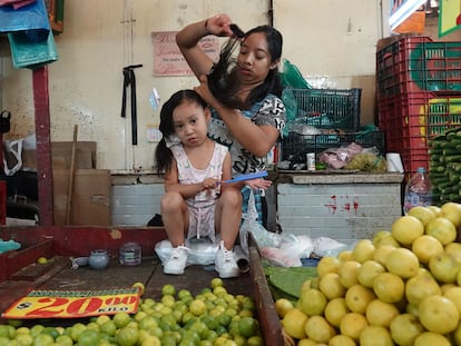 Una mujer peina a su hija en el mercado de la Merced, en Ciudad de México.