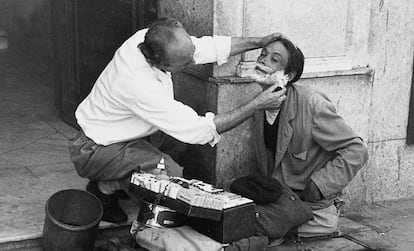 Madrid, 1950. Un barbero afeita en la calle a un vendedor de tabaco mutilado.