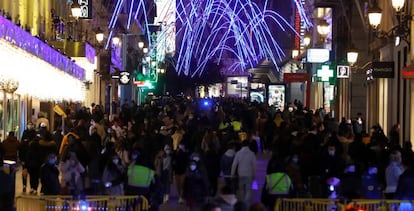 El virus no basta para cambiar algunos hábitos. Personas se congregan para hacer compras y disfrutar de las luces navideñas en la calle de Preciados, en Madrid. 