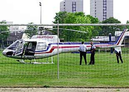 Tres policías observan el helicóptero utilizado para el intento de fuga.