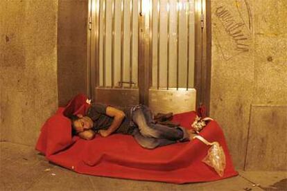 Un hombre duerme sobre una alfombra en la calle del Desengaño en la madrugada del viernes.