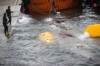 Dos miembros de la Unidad Especial de Intervención de la Guardia Civil trabajan en las labores de arrastre del 'narcosubmarino' al puerto.