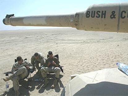 <i>Marines</i> de Estados Unidos descansan, ayer en el desierto de Kuwait, junto a un carro de combate M1A1 Abrams.