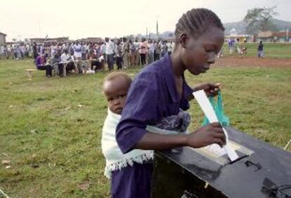 Una mujer, con su hijo a la espalda, deposita su voto para las elecciones presidenciales ugandesas ayer por la mañana en Kampala.