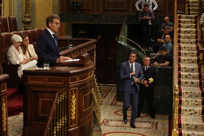 El presidente en funciones, Pedro Sánchez, entra en el hemiciclo, mientras el candidato popular, Alberto Núñez Feijóo, interviene desde la tribuna de oradores. 