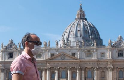 Un turista pasea con mascarilla por delante de la plaza de San Pedro, en el Vaticano.