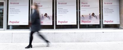 Una mujer camina delante de una sucursal de Banco Popular.