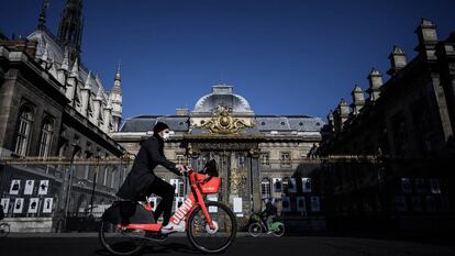 Homem passa de bicicleta diante do Palácio da Justiça, na Île de la Cité, Paris, em maio