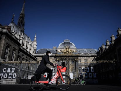 Homem passa de bicicleta diante do Palácio da Justiça, na Île de la Cité, Paris, em maio