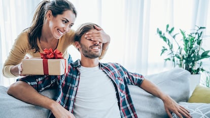 Una mujer dando un regalo por sorpresa a su novio.