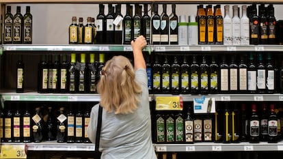 Una clienta de un supermercado español elige una botella de aceite de oliva.