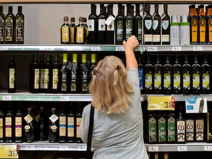 Una clienta compra aceite de oliva en un supermercado.