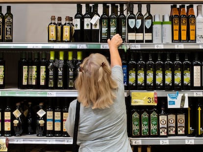 Una clienta de un supermercado español elige una botella de aceite de oliva.