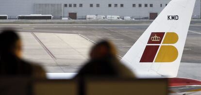 Dos personas ante un avión de Iberia.