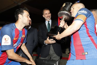 Don Felipe hace entrega del trofeo a Andrés Iniesta en presencia de Busquets en la final de la Copa del Rey tras imponerse el Barcelona al Deportivo Alavés en el estadio Vicente Calderón, el 27 de mayo de 2017.