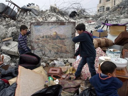 Niños palestinos sacan un cuadro que muestra la cúpula de la roca y las murallas de la Ciudad Vieja de entre los escombros de su casa, en Jerusalén este.