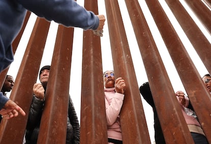 Immigrantes solicitantes de asilo frente al muro fronterizo en San Diego, California, en mayo de 2023.