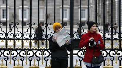 Dos turistas consultan un plano de Madrid ante el Palacio Real.