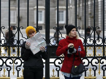 Dos turistas consultan un plano de Madrid ante el Palacio Real.