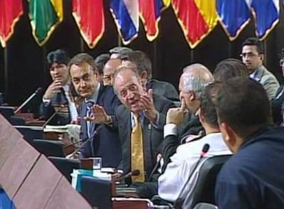 El Rey, mano en alto, exige malhumorado  a Chávez (de espaldas, en primer plano) que se calle.
