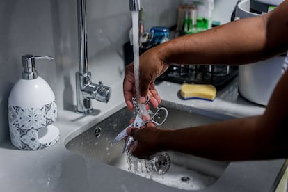 Una empleada de hogar friega cubiertos de cocina.