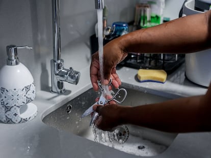 Una empleada del hogar friega cubiertos de cocina.