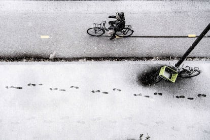 Pisadas en una acera de Róterdam mientras un hombre circula con su bicicleta.