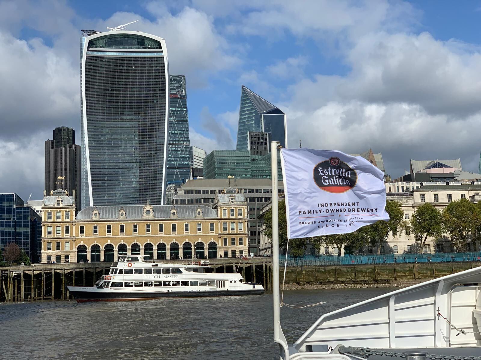 Una embarcación con la bandera de Estrella Galicia atraviesa el río Tamesis, en Londres.