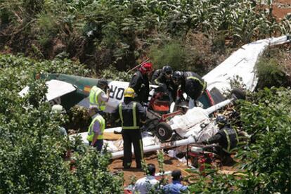 Varios bomberos trabajan en el fuselaje de una avioneta modelo Cessna 172 N para extraer los cadáveres de los ocupantes.