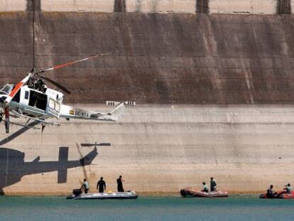 El helic&oacute;ptero siniestrado es elevado por una gr&uacute;a en la presa del embalse de Forata.