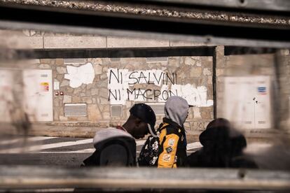Tres migrantes pasan junto a un grafiti en el que puede leerse 'Ni Salvini, ni Macron', en la localidad de Claviere (italia), a 100 kilómetros de Turín, el 21 de octubre de 2018.