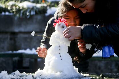 Varios niños juegan con la nieve en la colina de San Cristóbal en Santiago de Chile, el 16 de julio de 2017.