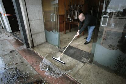 Un hombre limpia su restaurante próximo a la playa de Riazor, en A Coruña, tras verse afectado por el agua del mar. 