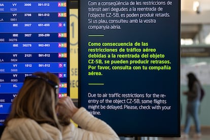 Una viajera en el aeropuerto de El Prat consulta el panel que informa de los retrasos en motivo del cohete.