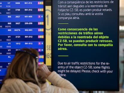 Una viajera en el aeropuerto de El Prat consulta el panel que informa de los retrasos en motivo del cohete.