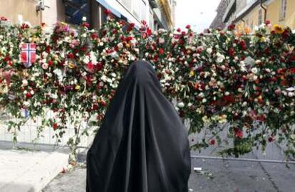 Una mujer de fe musulmana se para delante de la catedral de Oslo para observar un homenaje floreal para las víctimas del atentado del pasado viernes. Hoy el abogado de Anders Behring Breivik, el autor de la matanza, ha alegado que su cliente padece "problemas mentales"