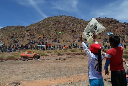 Dos niños bolivianos agitan una bandera del Dakar